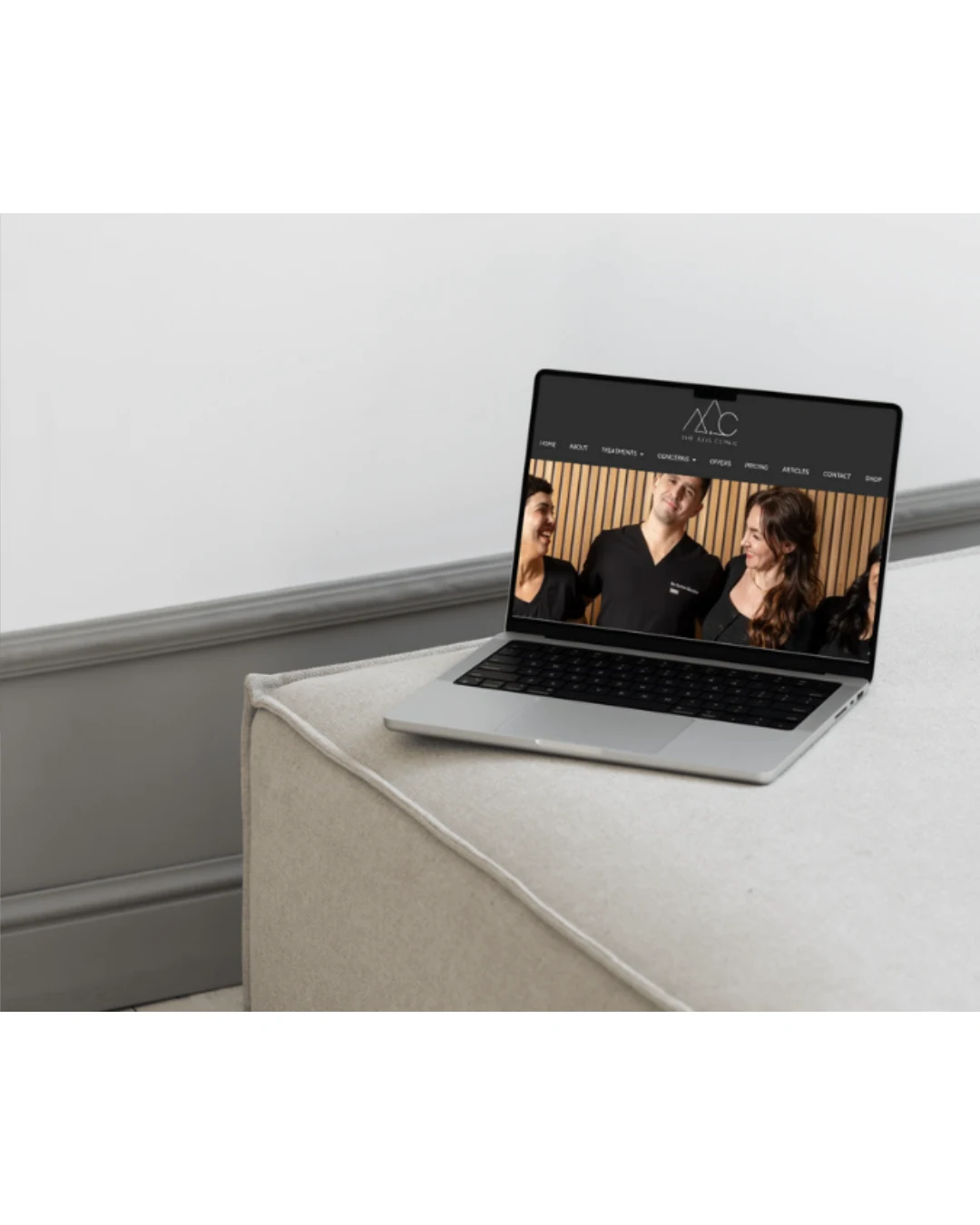 Laptop displaying Axis Clinic website homepage featuring team of aesthetic practitioners.