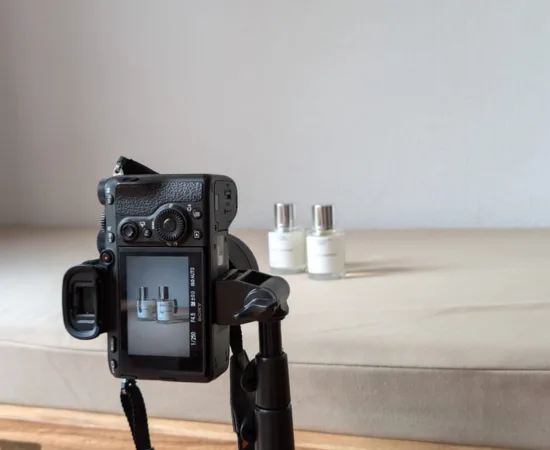 Camera on tripod photographing perfume bottles, representing Marketing Valley’s product content creation services.