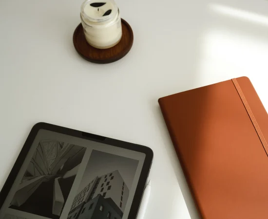 Tablet with architectural visuals, orange notebook, and candle on desk, symbolising Marketing Valley’s Mini Branding creative process.